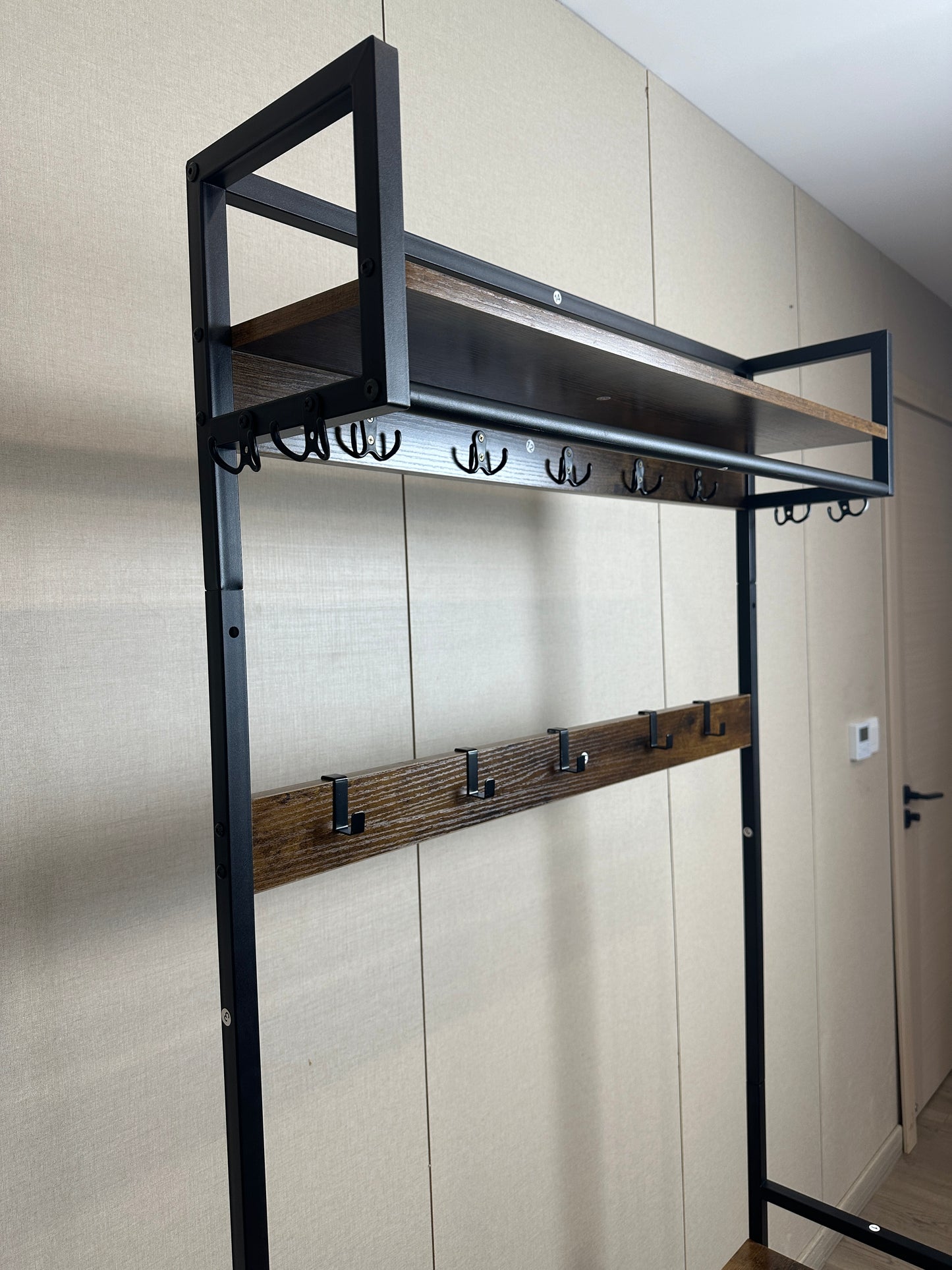 Industrial coat rack with dark wood shelves and black metal frame offering ample hanging space