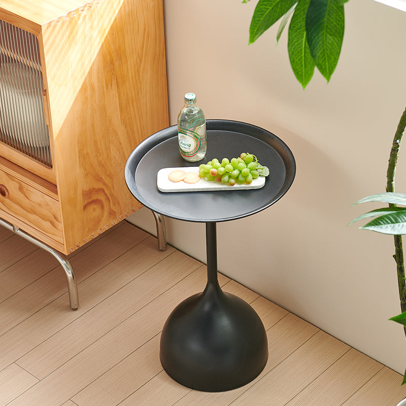 Modern black metal side table with a round tray top holding grapes and a drink