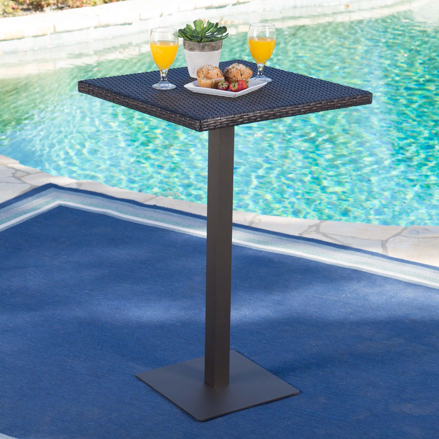 Woven wicker outdoor bar table with dark brown top and dark metal pedestal base