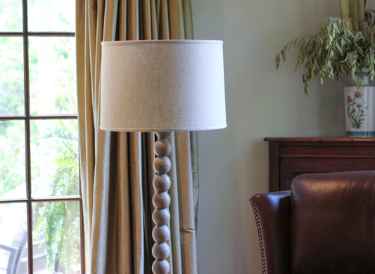Cream linen drum shade floor lamp with stacked wooden sphere base