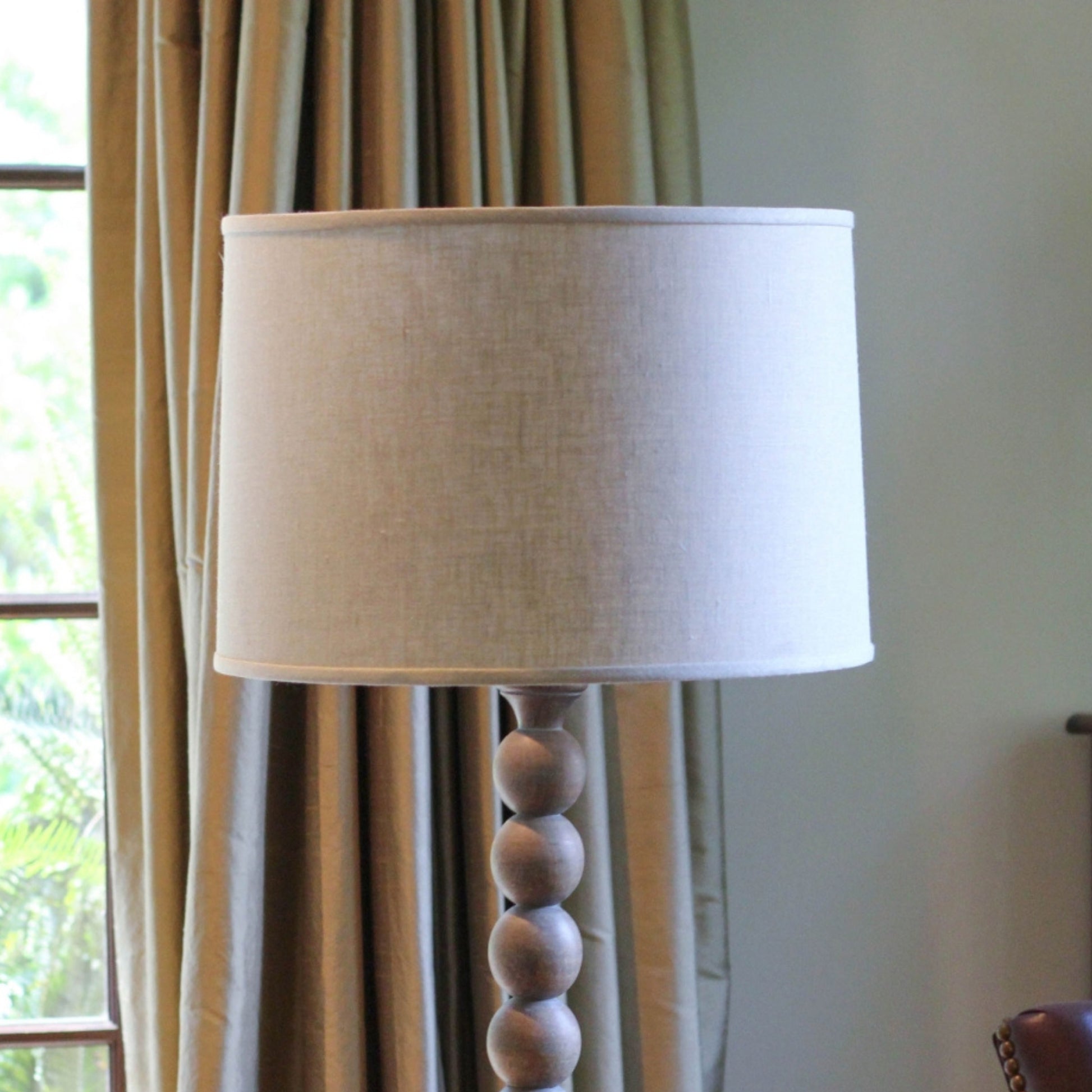 Beige linen drum lampshade with a stacked wooden ball base floor lamp
