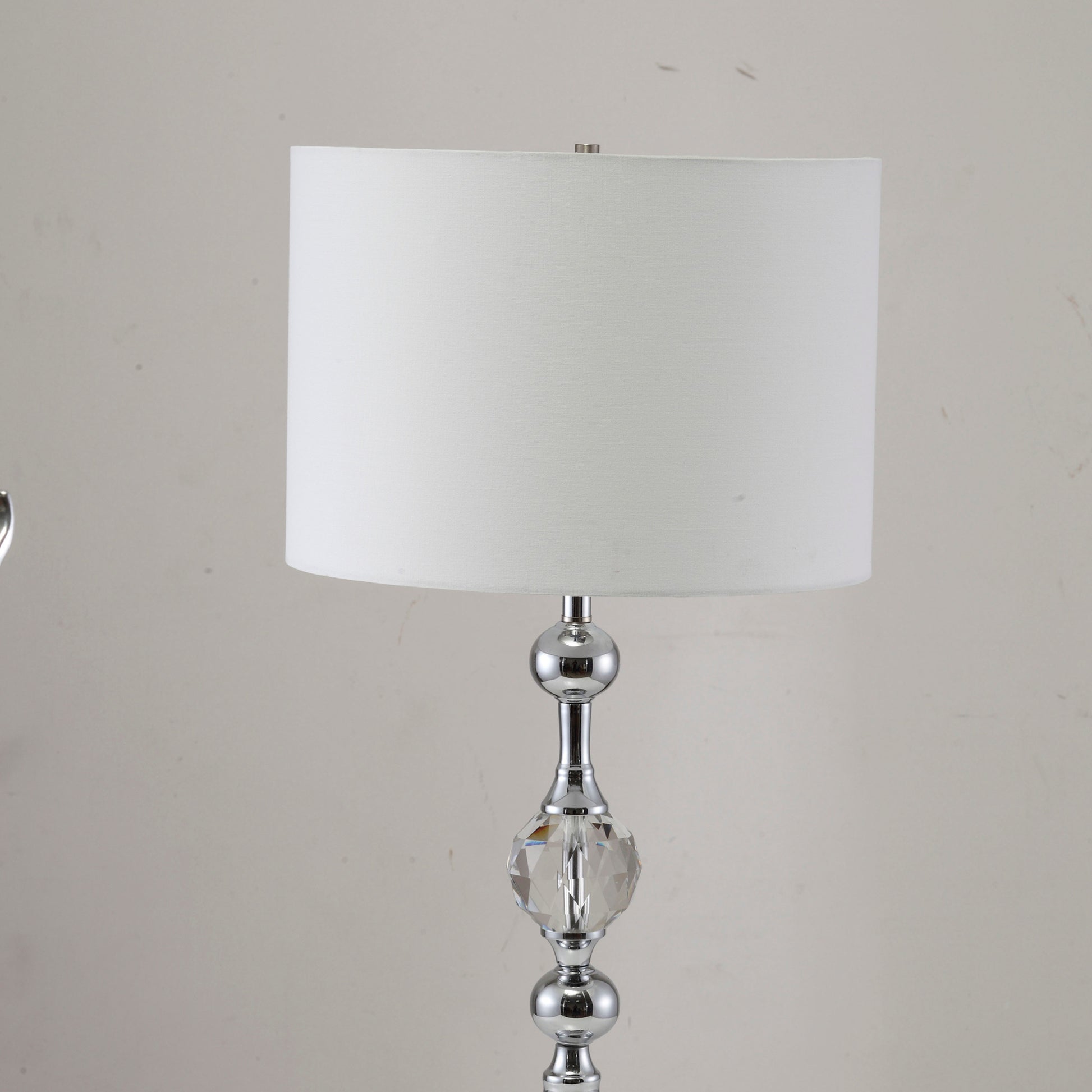 Polished chrome table lamp with a crystal accent and white fabric shade