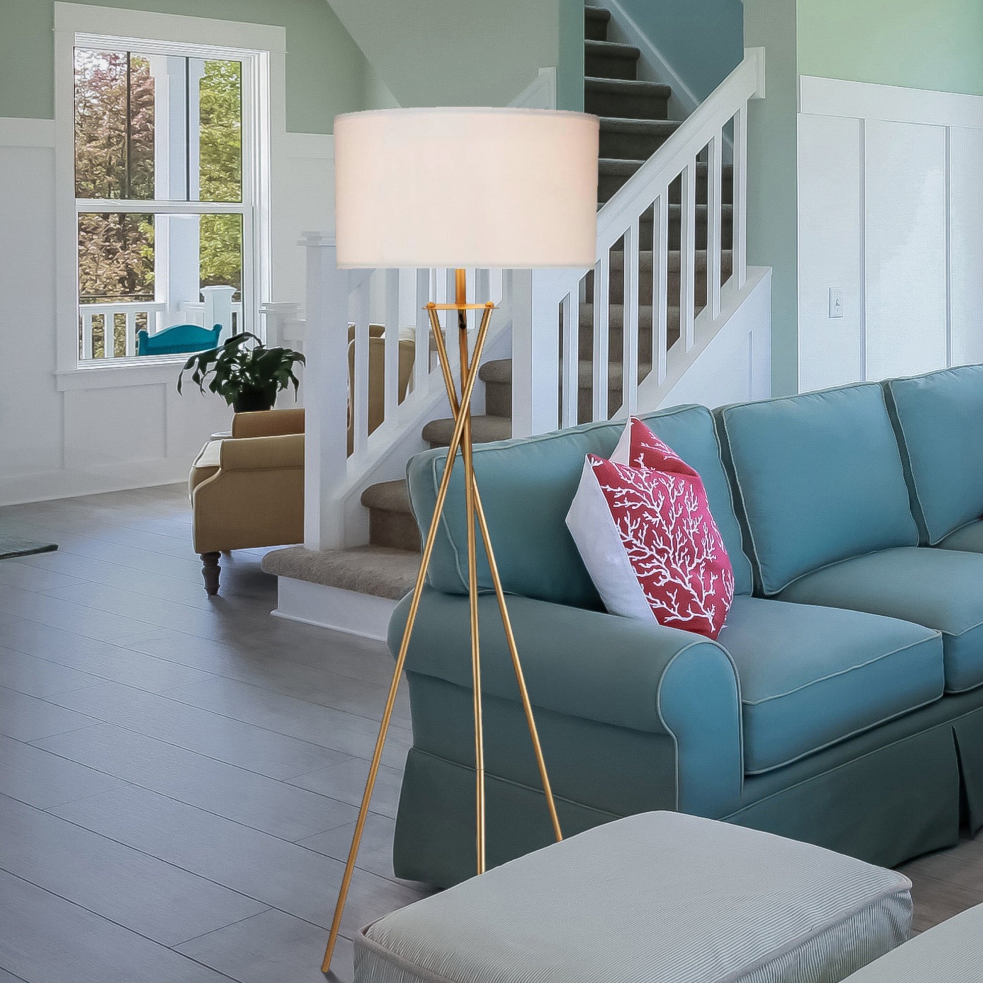 Elegant gold tripod floor lamp with cream drum shade illuminating a modern living room
