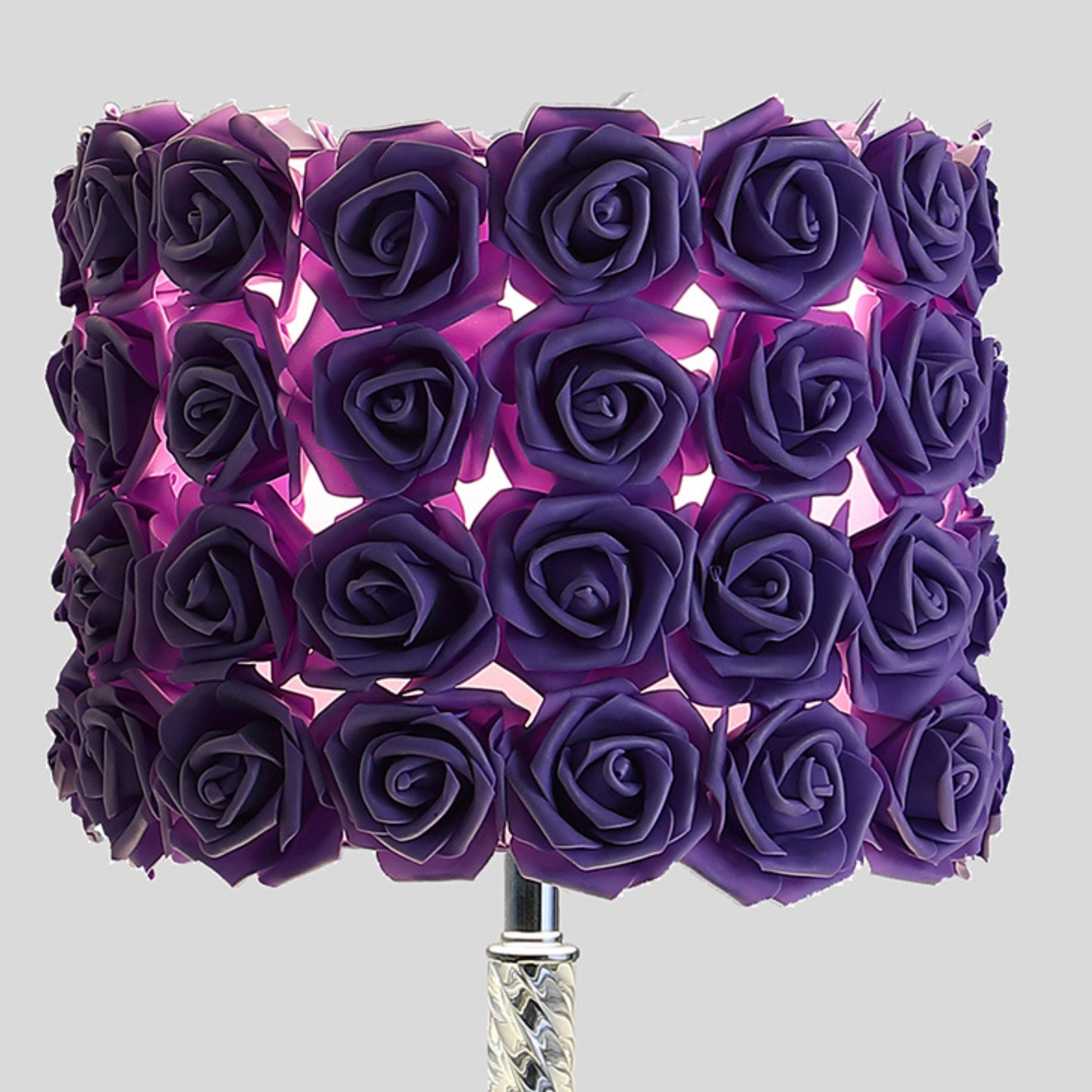 Purple rose lampshade with intricate floral design casting a soft glow