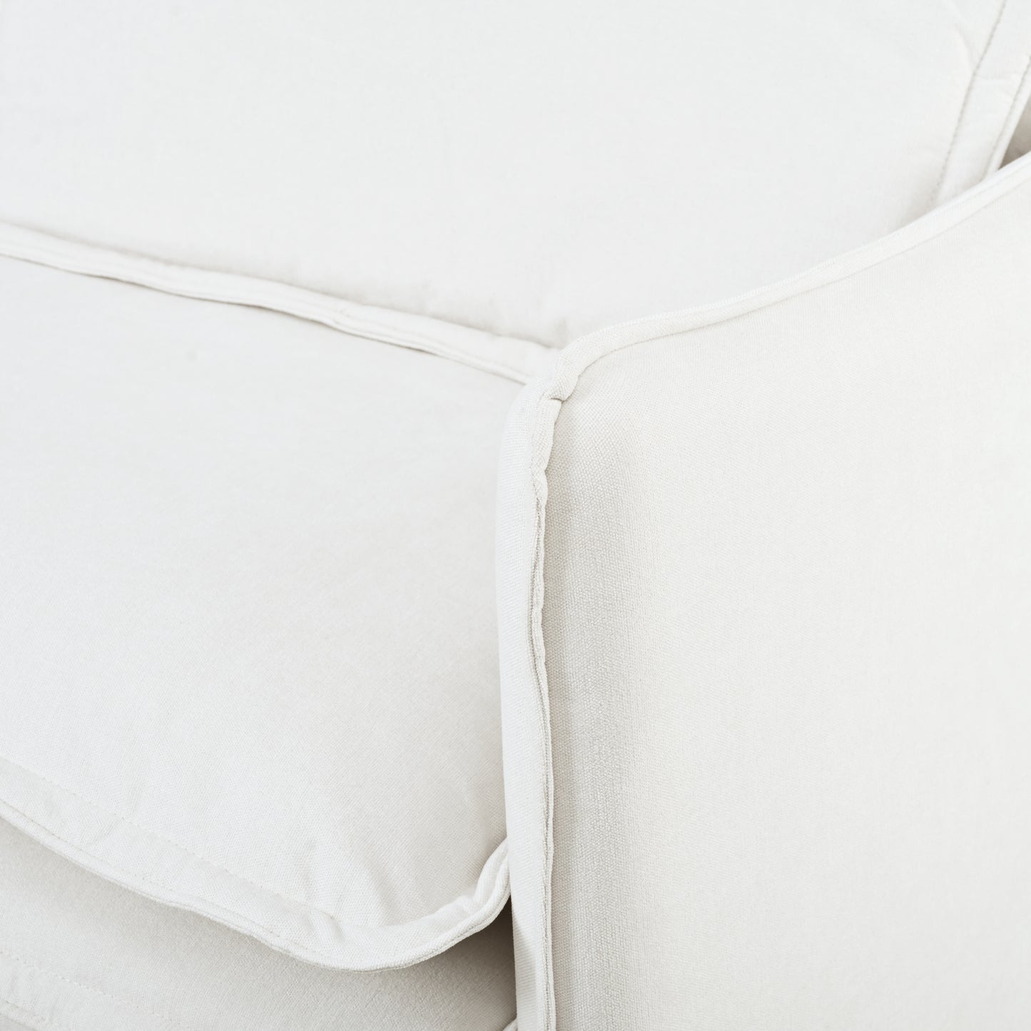 Cream linen sofa detail with piped seam offering a plush and comfortable seating option