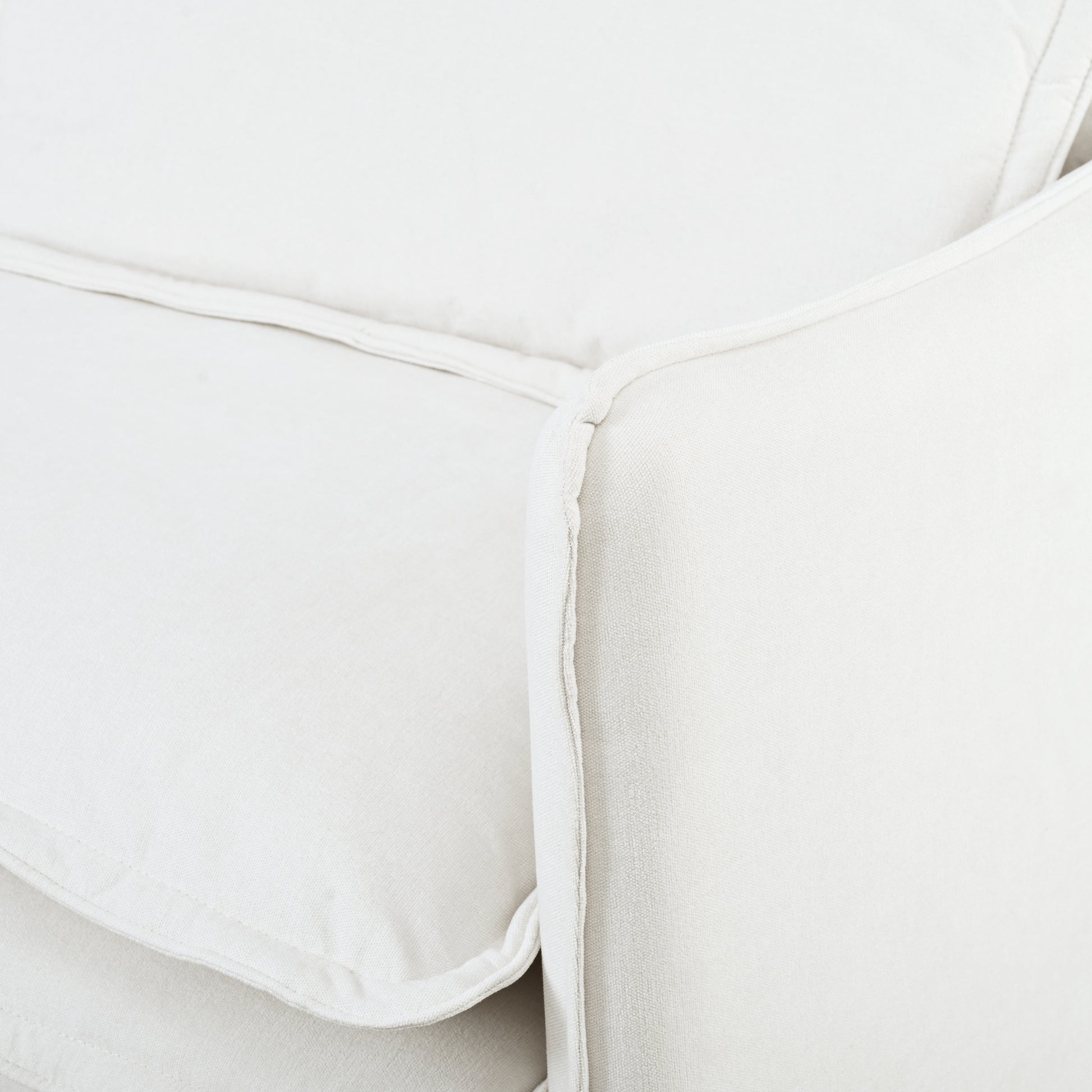 Cream linen sofa detail with piped seam offering a plush and comfortable seating option