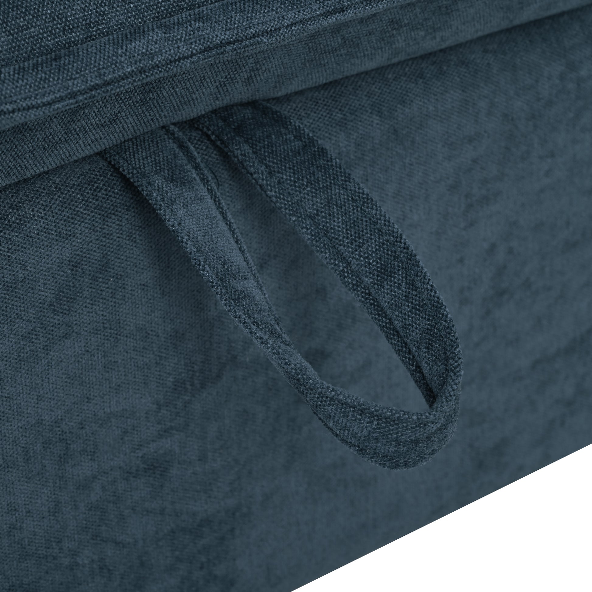 Closeup of a dark blue fabric ottoman with a pull strap for easy lifting
