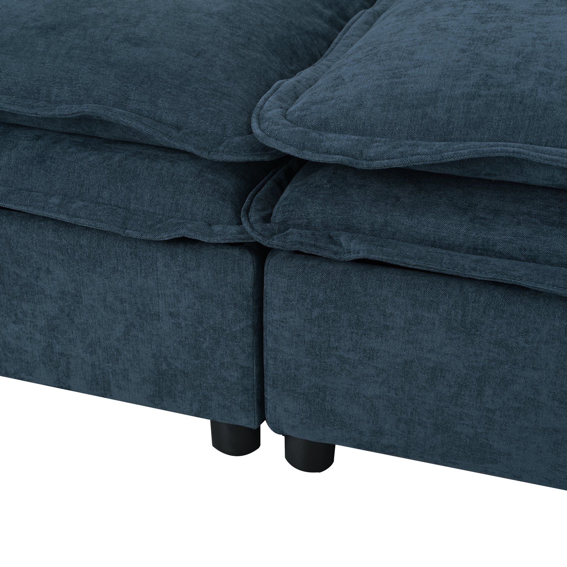 Close up of a plush navy blue fabric sofa with thick soft cushions and black cylindrical feet