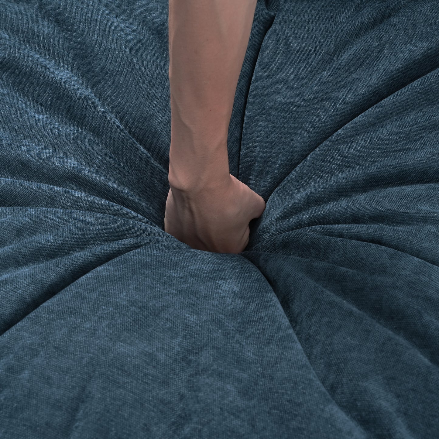 Hand pressing into deep blue textured fabric showing material softness and comfort