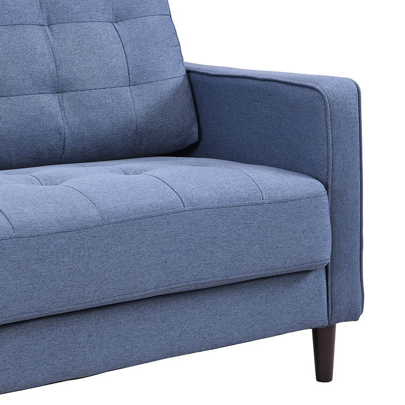 Closeup of a blue upholstered sofa arm with tufted seat cushions and dark wooden legs