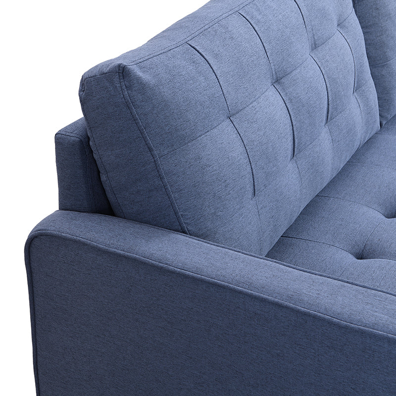 Closeup of a tufted navy blue fabric sofa armrest and back cushion