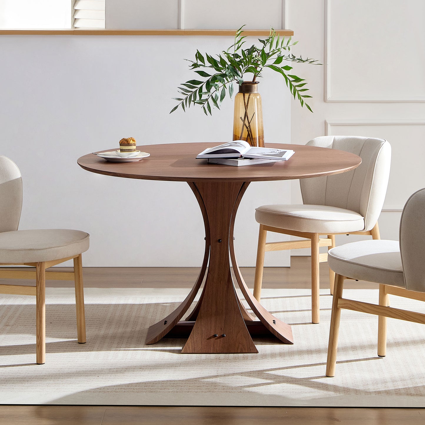 Round walnut dining table with sculptural wood base seating four people
