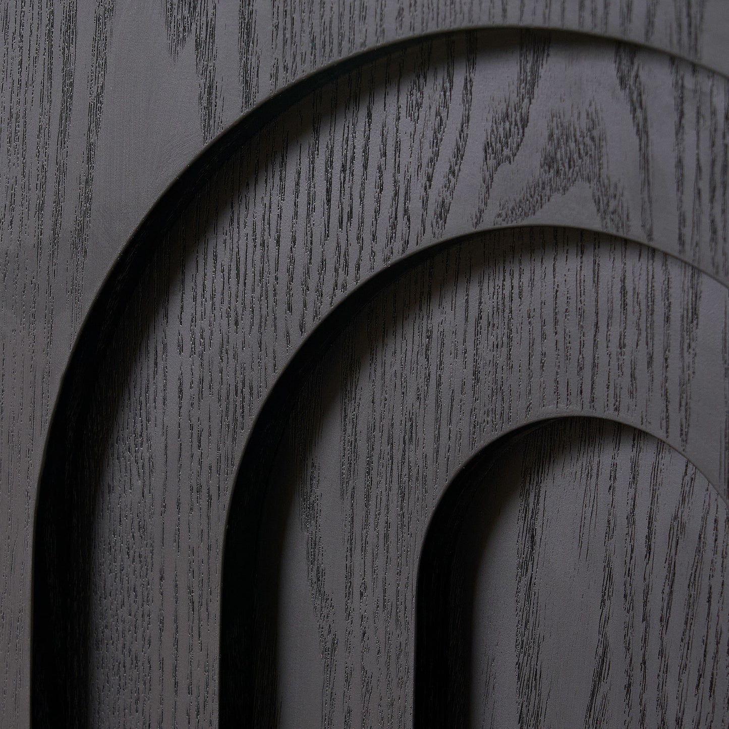 Black carved wood panel with arched details and visible grain