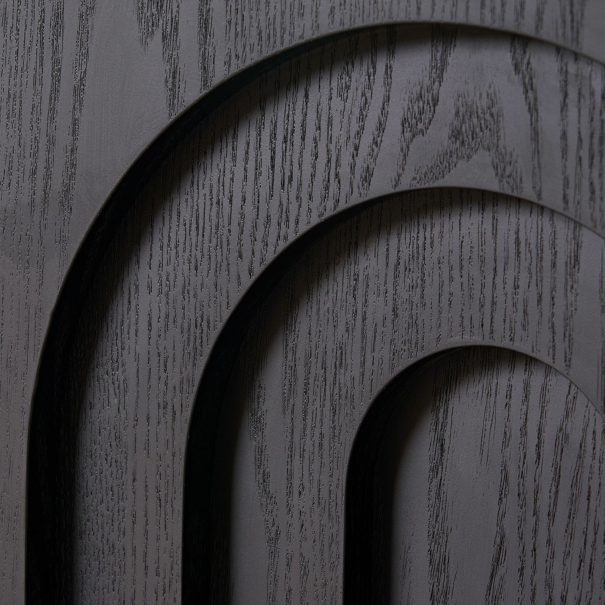 Black carved wood panel with arched details and visible grain