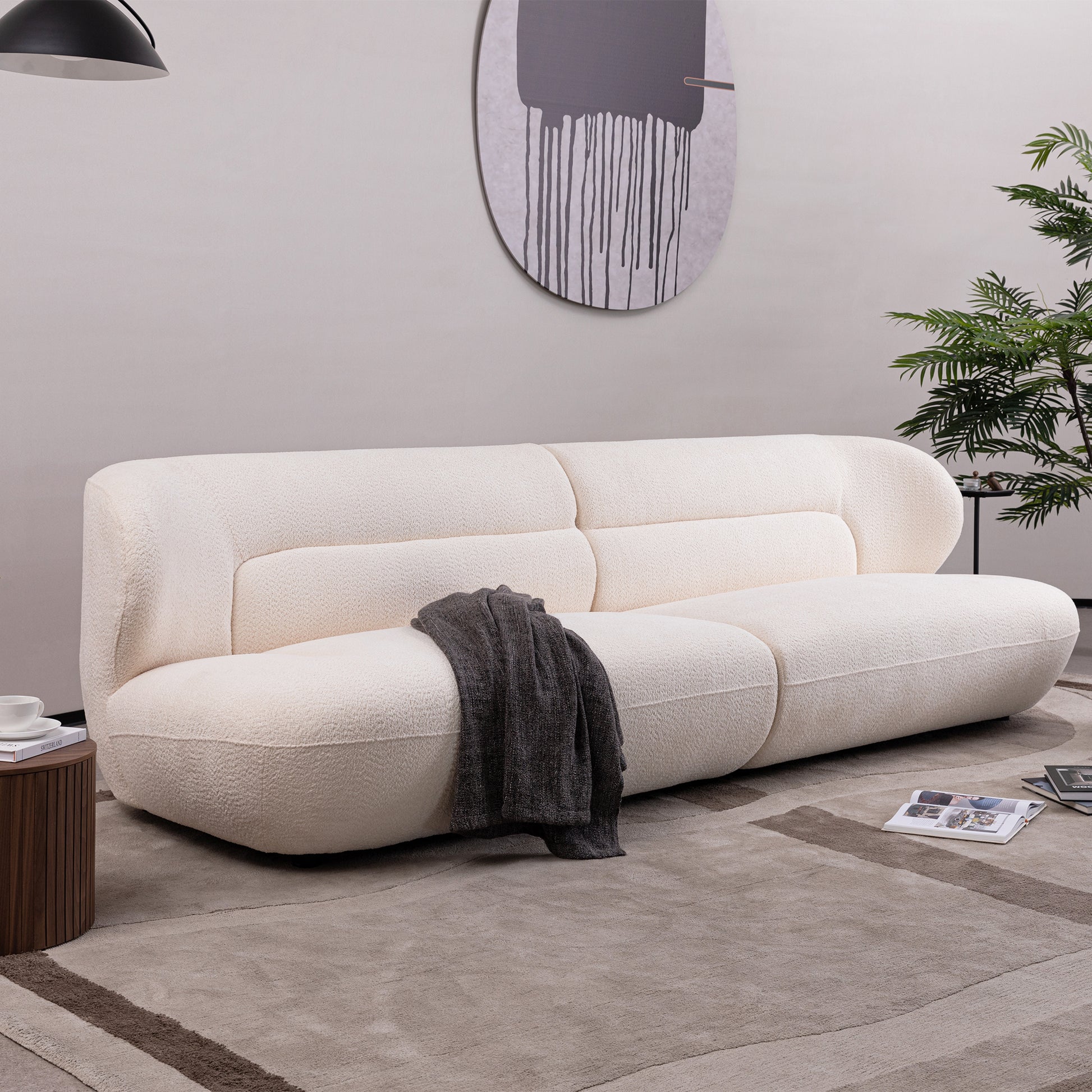 Cream boucle fabric sofa with curved arms and a dark grey throw blanket