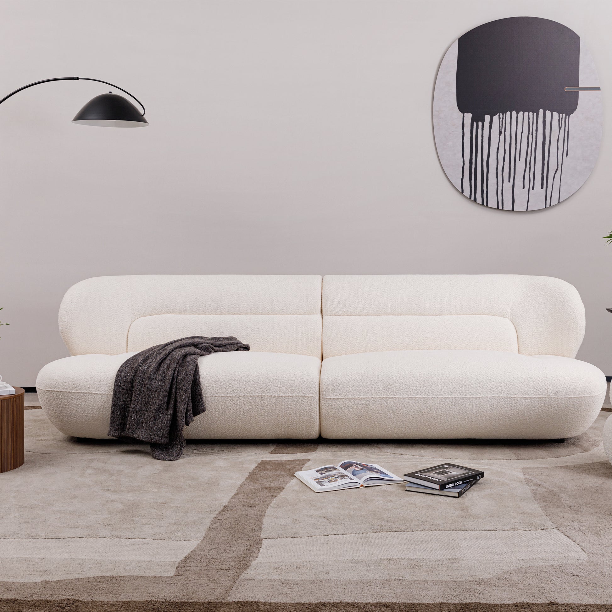 Cream boucl fabric sofa with curved arms and a charcoal throw blanket