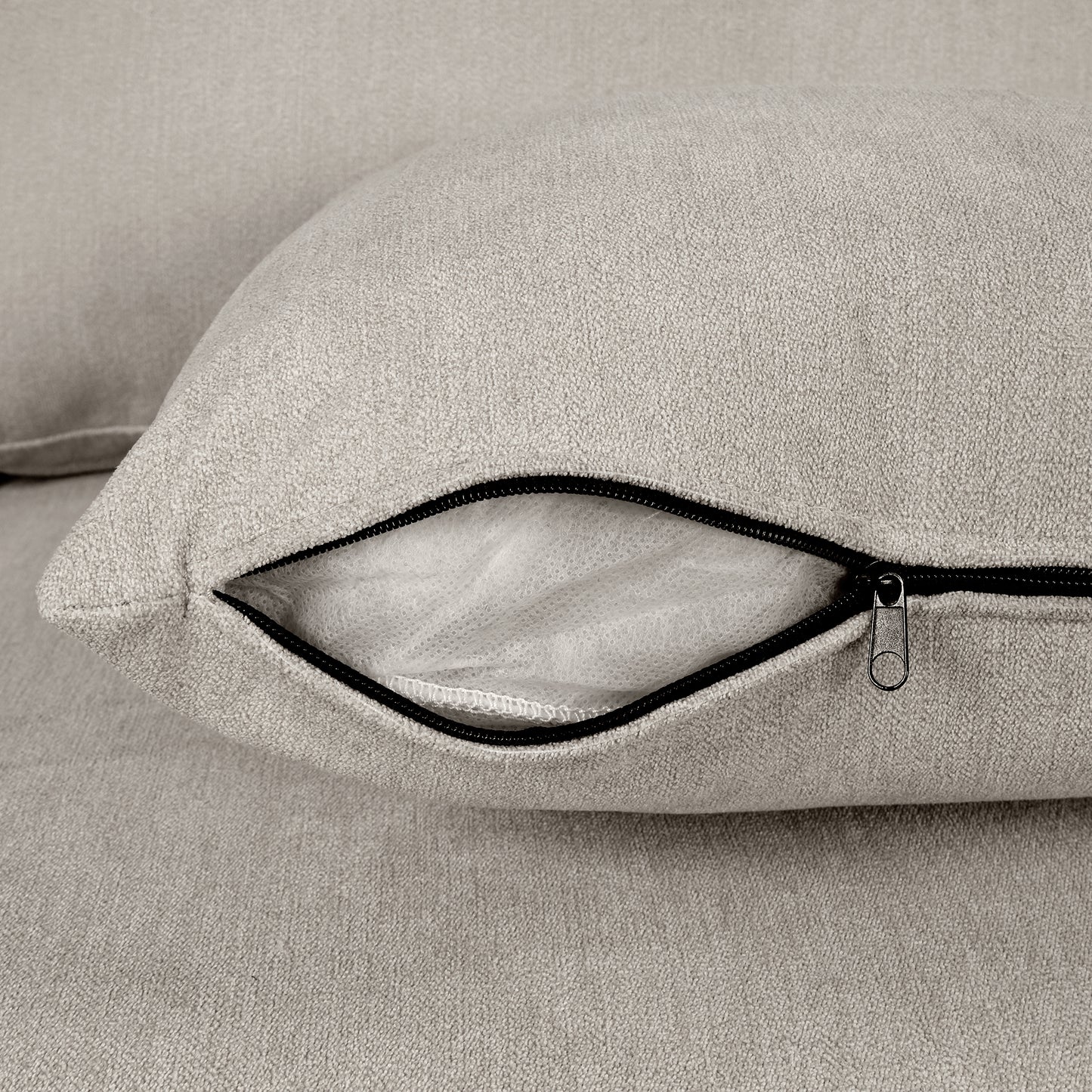 Closeup of a light beige textured fabric sofa cushion with an open zipper revealing interior stuffing