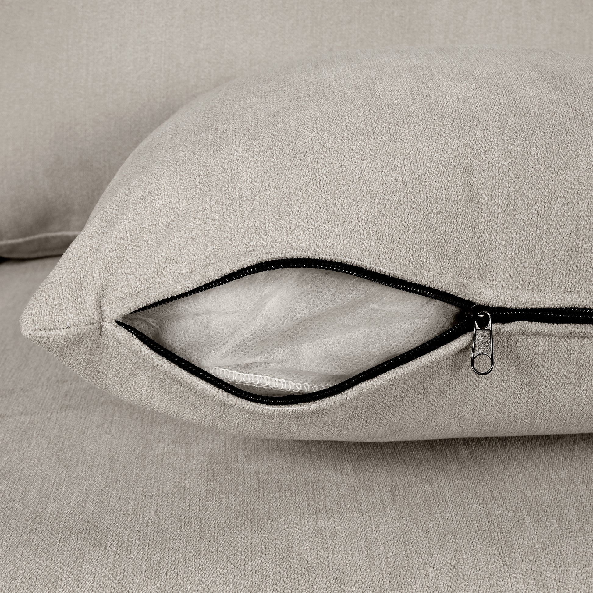Closeup of a light beige textured fabric sofa cushion with an open zipper revealing interior stuffing