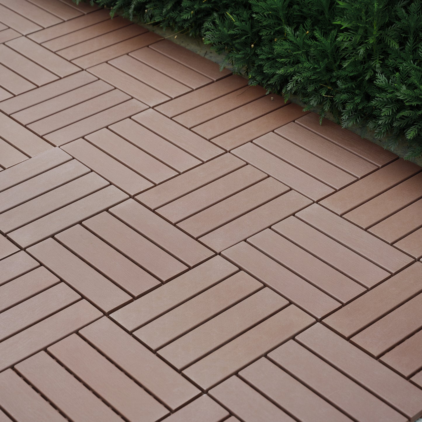 Brown composite deck tiles in a herringbone pattern ideal for outdoor patios
