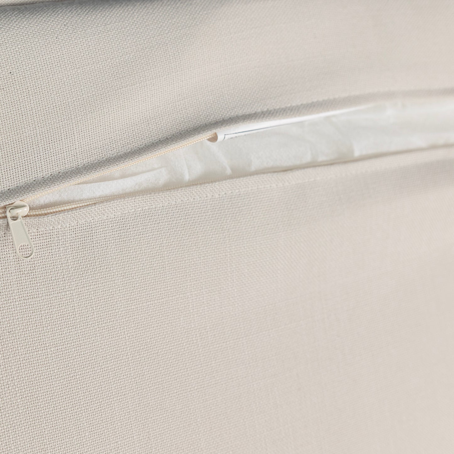 Closeup of a beige textured fabric with an open zipper detail showcasing a cushion cover