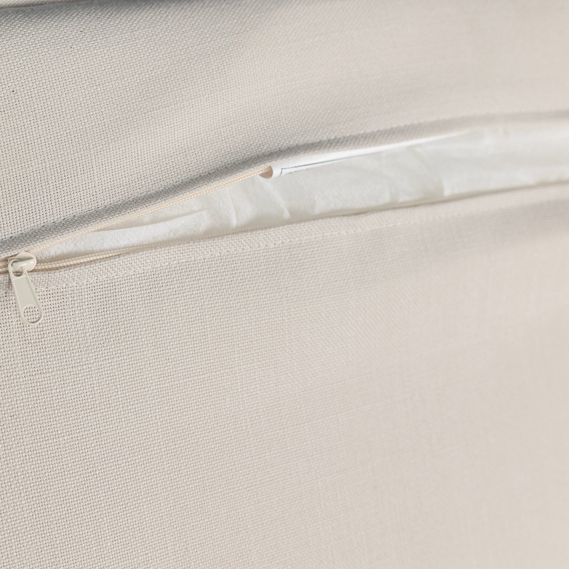Closeup of a beige textured fabric with an open zipper detail showcasing a cushion cover