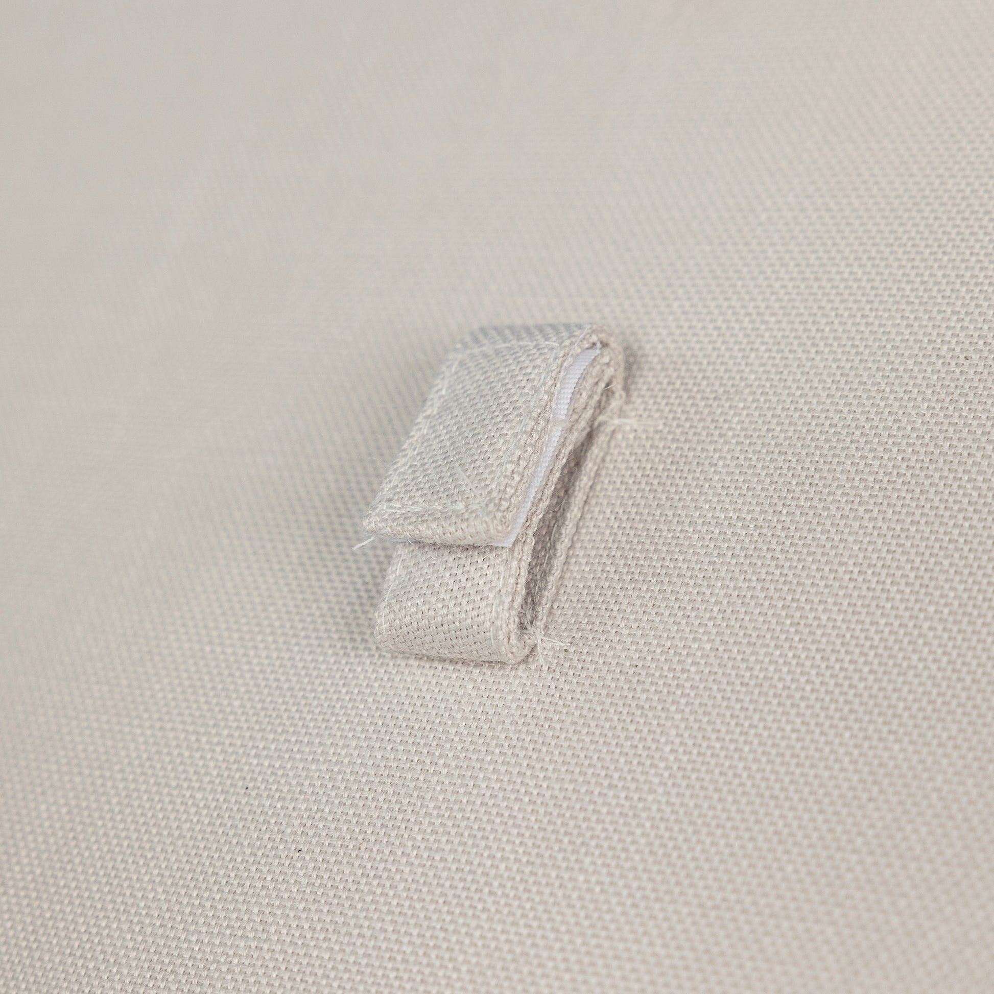 Closeup of beige canvas fabric with a folded fabric loop detail