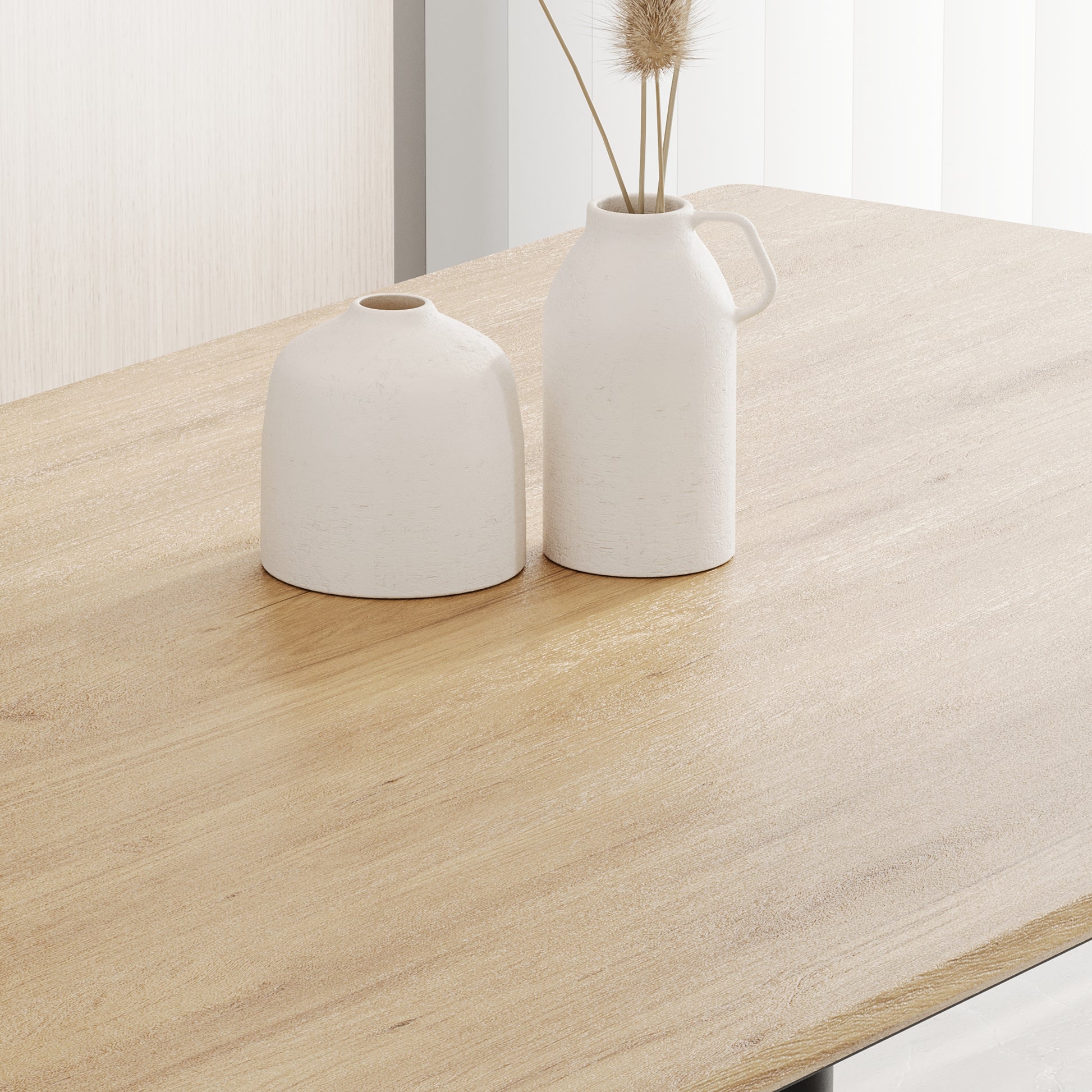 Modern light oak dining table with textured white ceramic vases and dried grass centerpiece