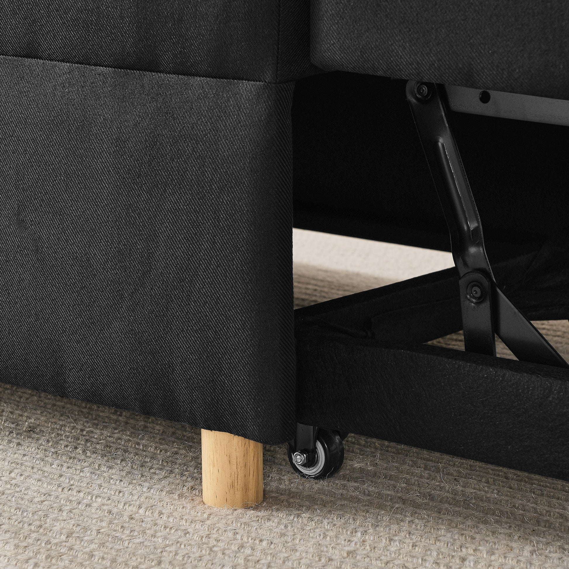 Black upholstered sofa base with exposed metal mechanism and casters