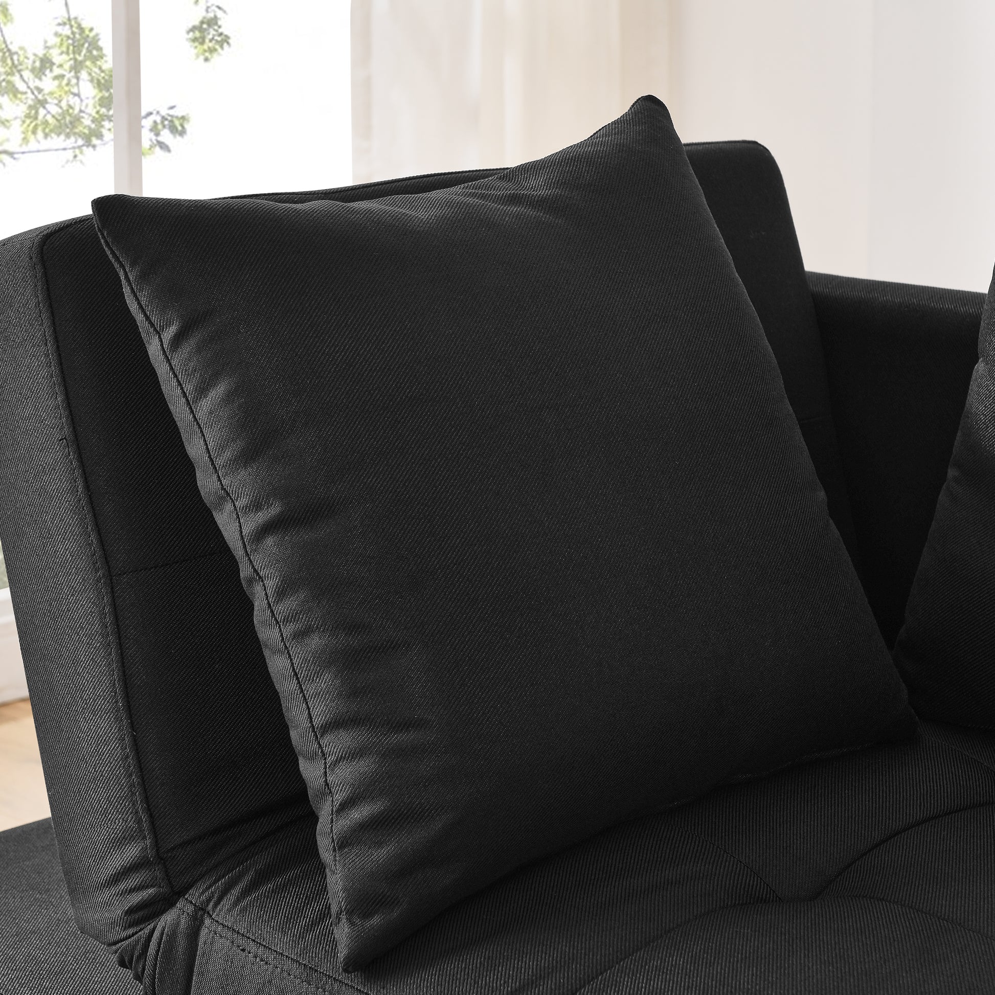 Black upholstered sofa with textured fabric and a matching throw pillow