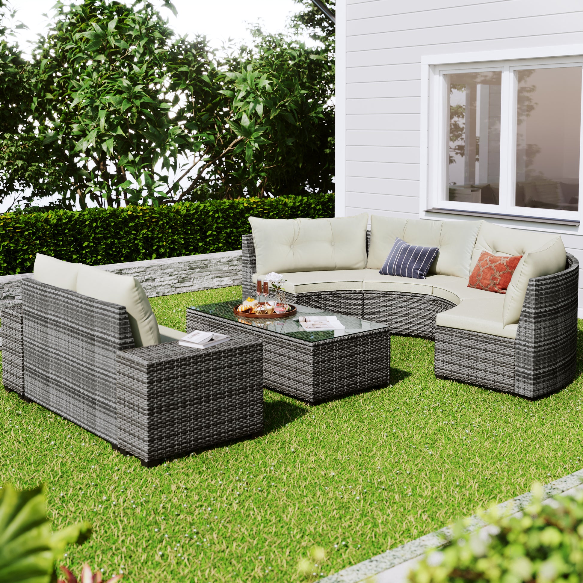 Grey wicker outdoor sofa set with cream cushions and glass coffee table on a green lawn