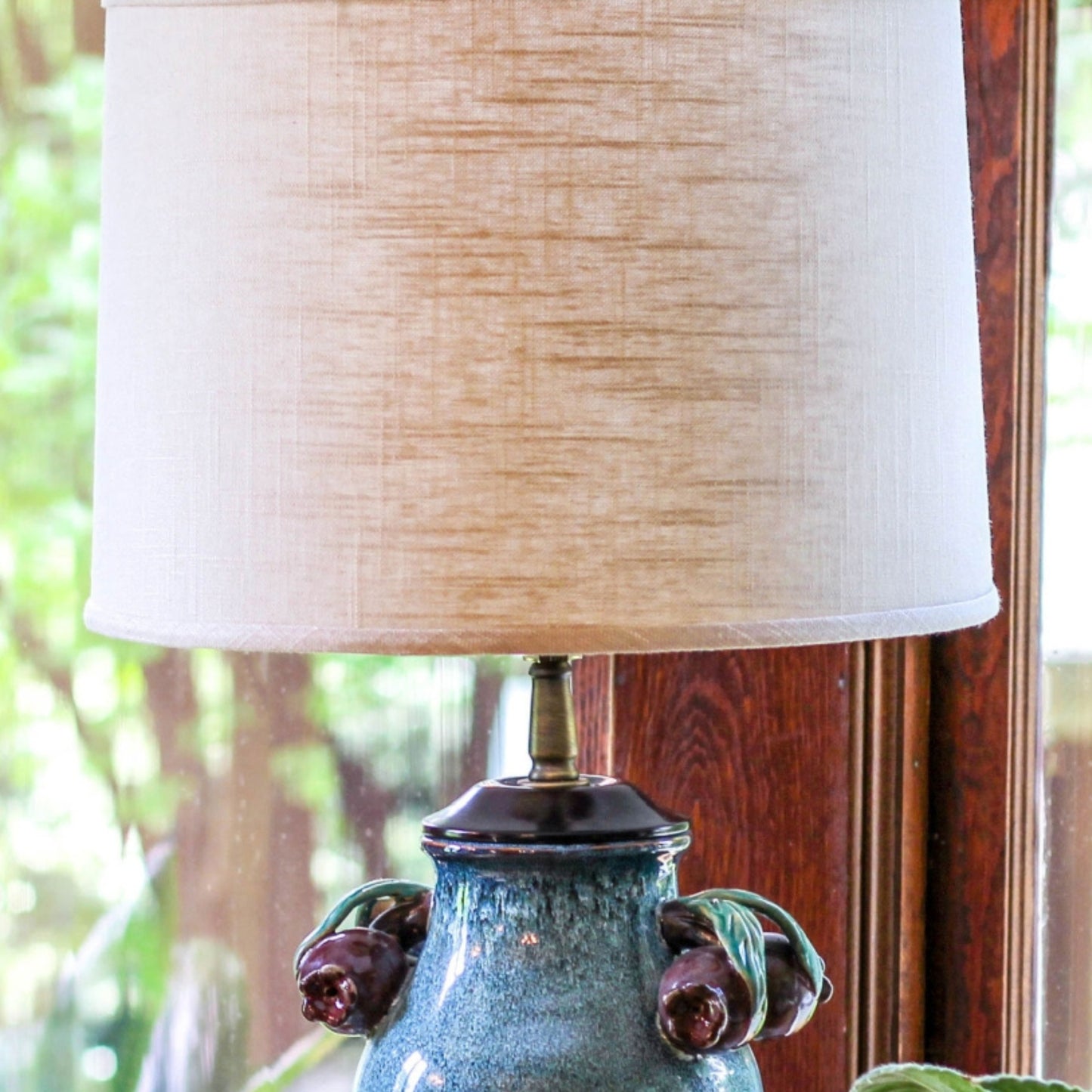Textured linen drum lampshade in beige with antique brass accents on a teal ceramic base