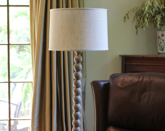 Tall beaded wood floor lamp with a natural linen shade ideal for living room lighting