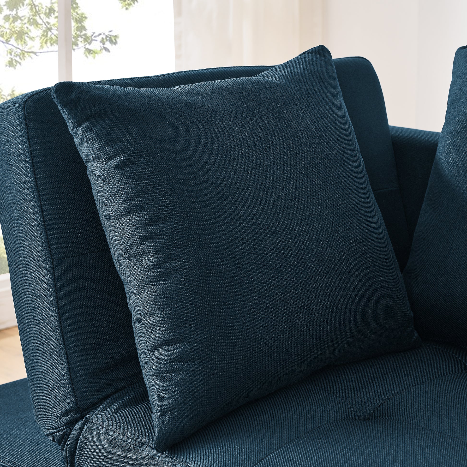 Closeup of a dark blue textured fabric sofa with a plush throw pillow perfect for modern living rooms