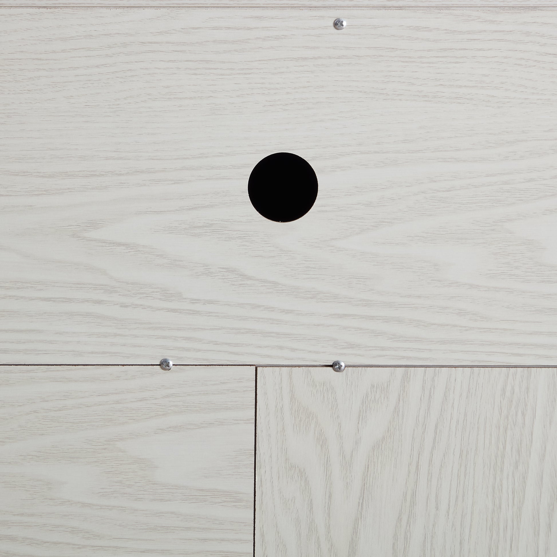 Closeup of light oak wood veneer panel with cable management hole