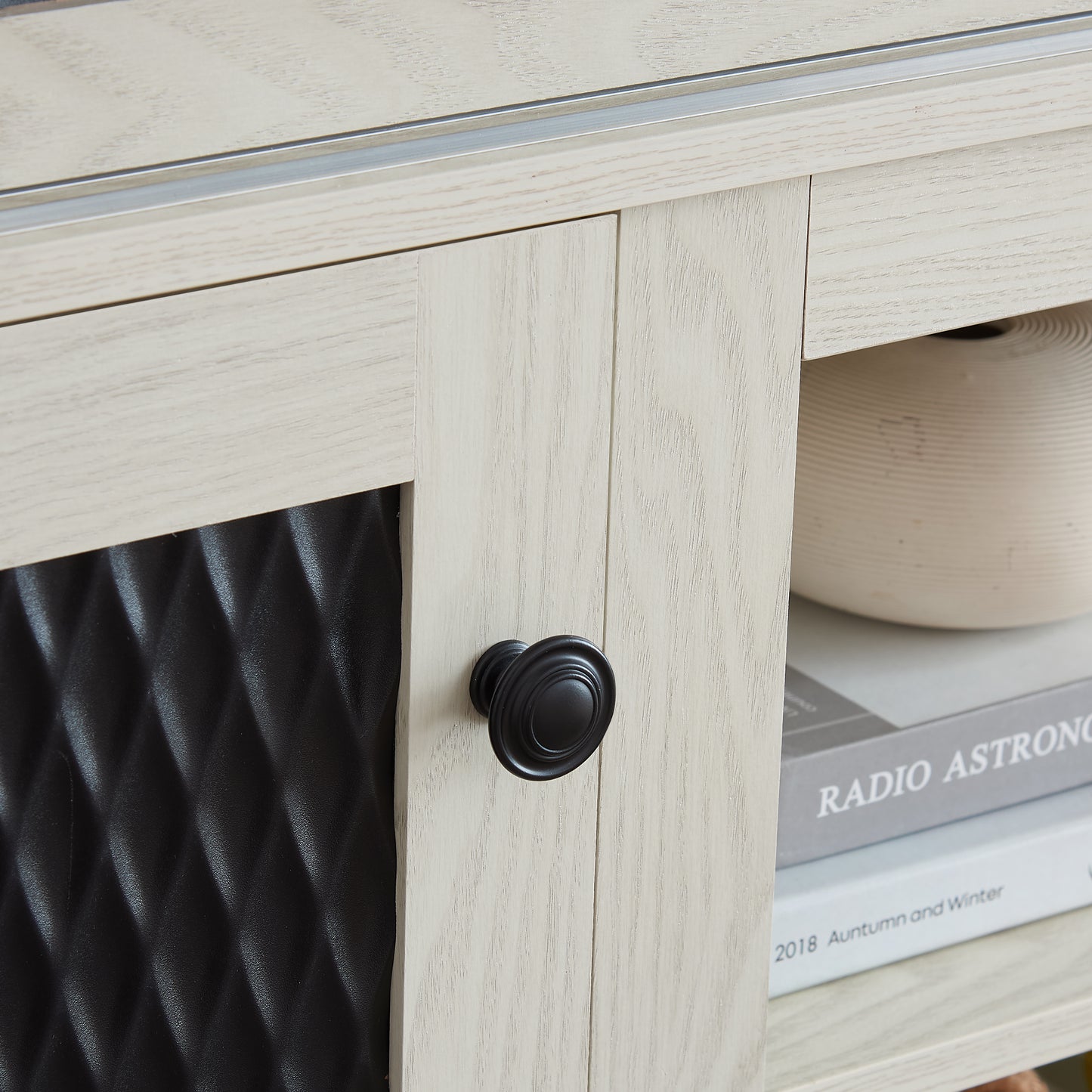 Light wood grain cabinet door with black oval knob and textured black panel detail