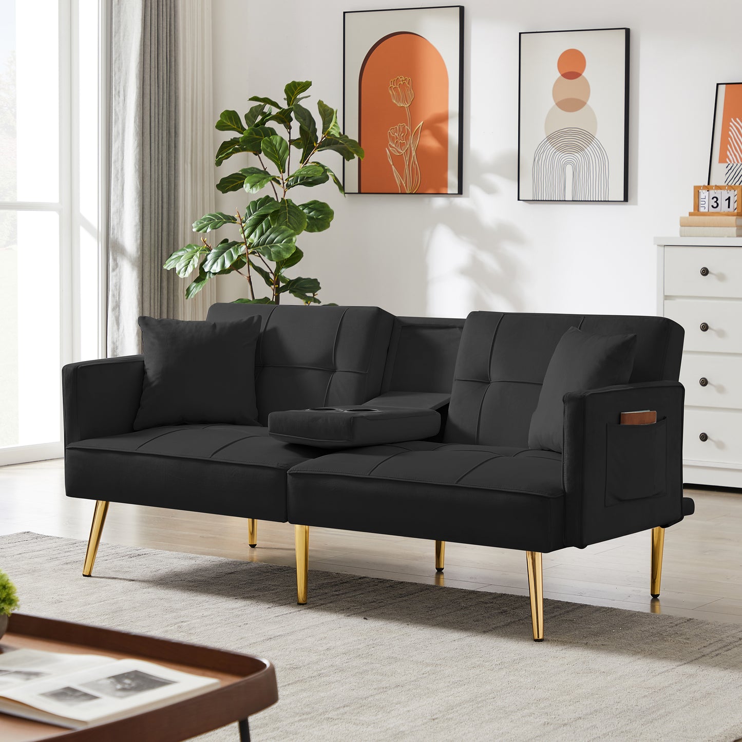 Black velvet sofa bed with tufted cushions and gold legs featuring a convenient dropdown armrest with cup holders