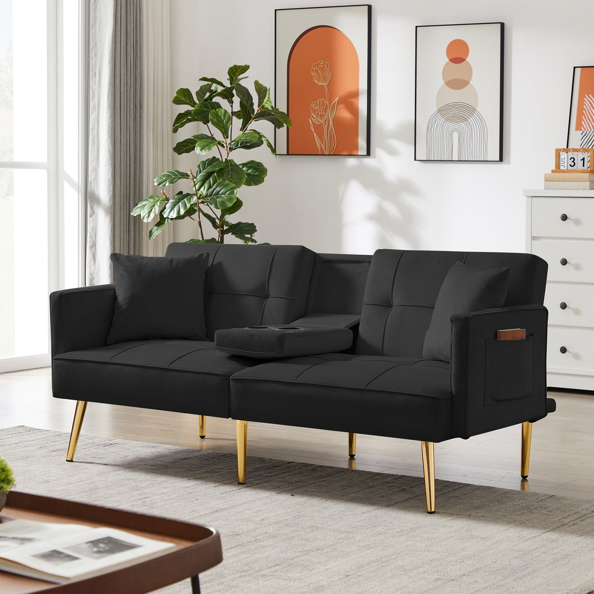 Black velvet sofa bed with tufted cushions and gold legs featuring a convenient dropdown armrest with cup holders