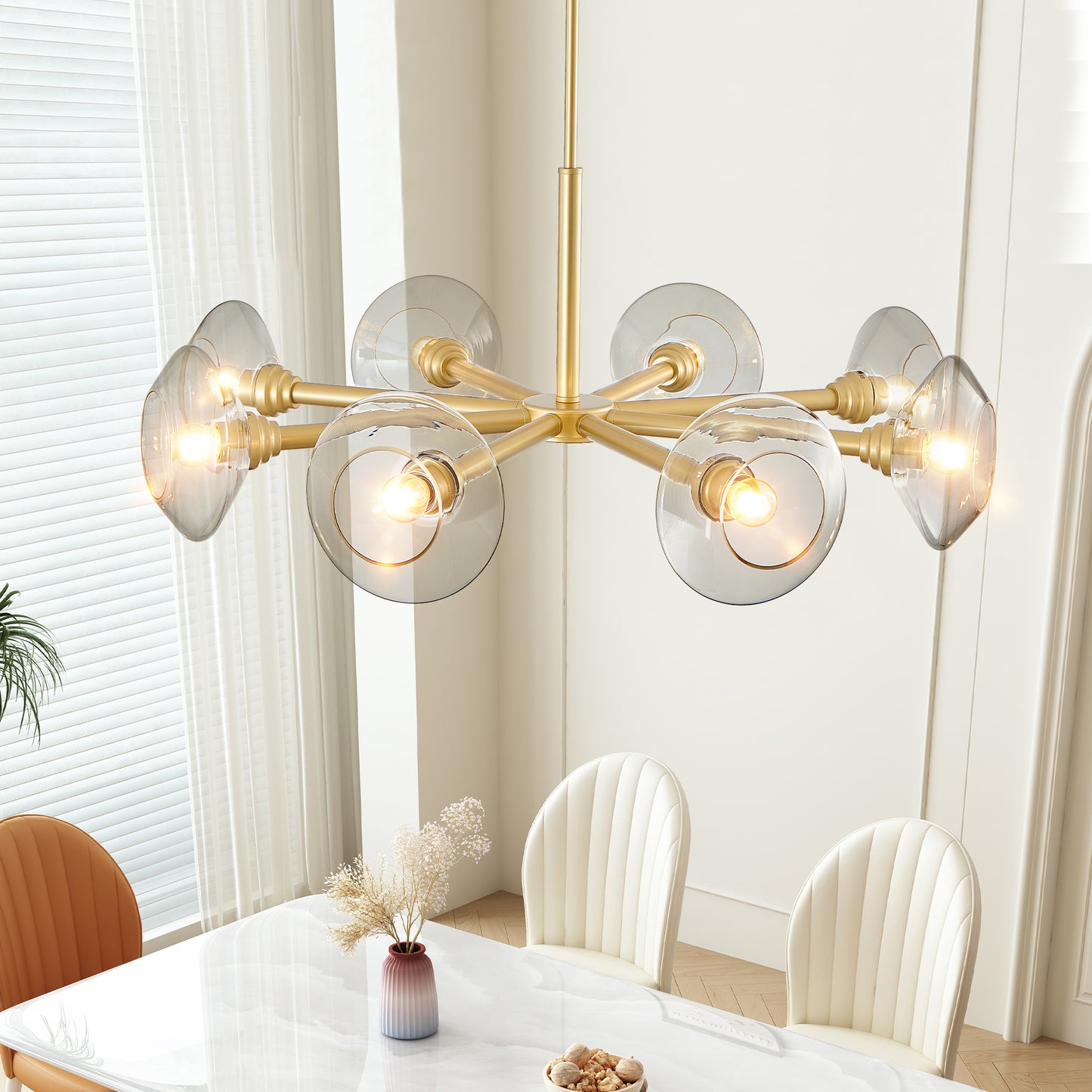 Modern gold chandelier with clear glass globes suspended above a dining table