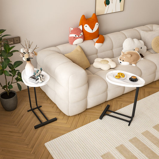 White oval side table with a black metal Cshaped base holding books and figurines