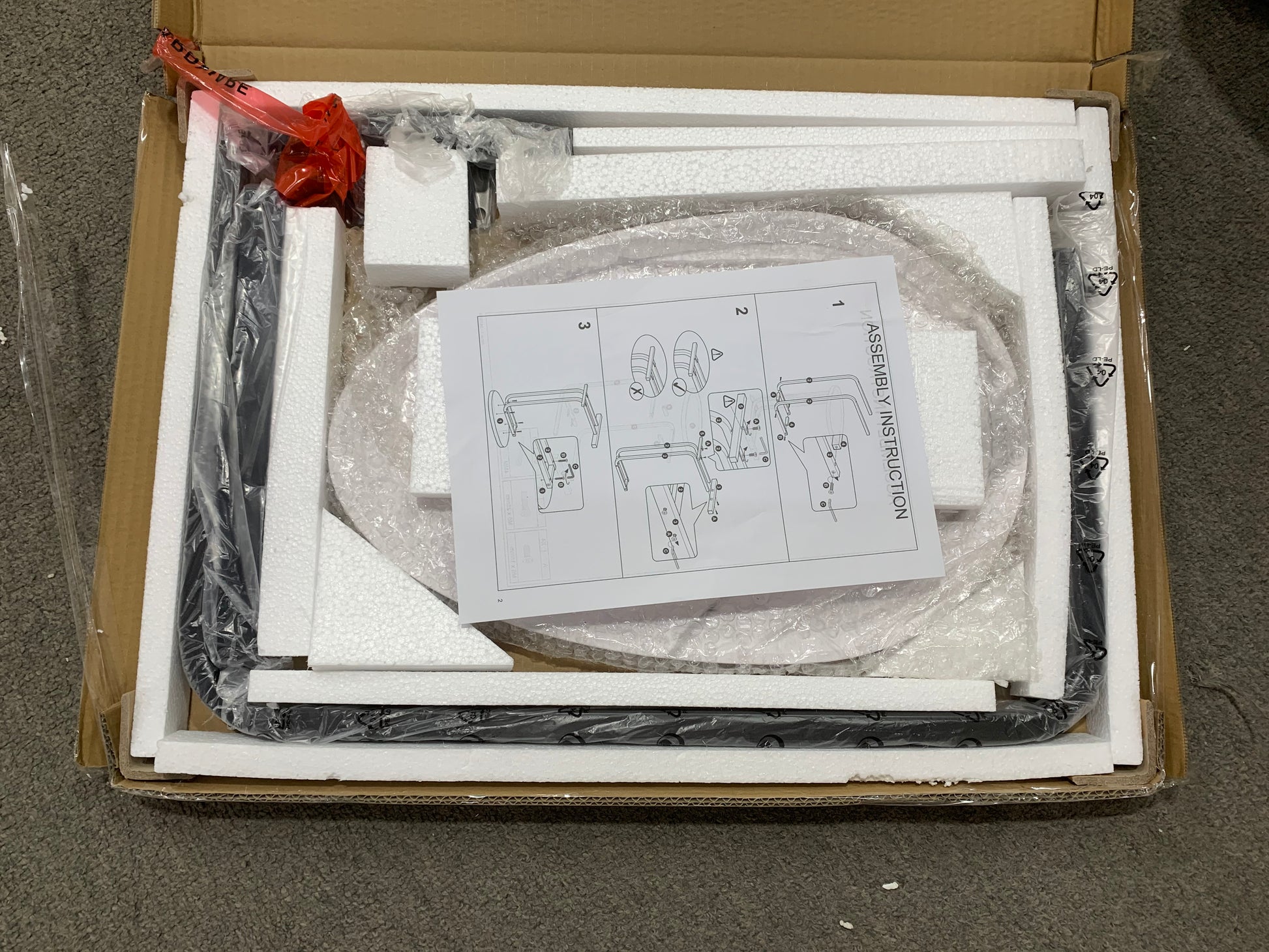 Unpacked black metal lamp base and assembly instructions in box