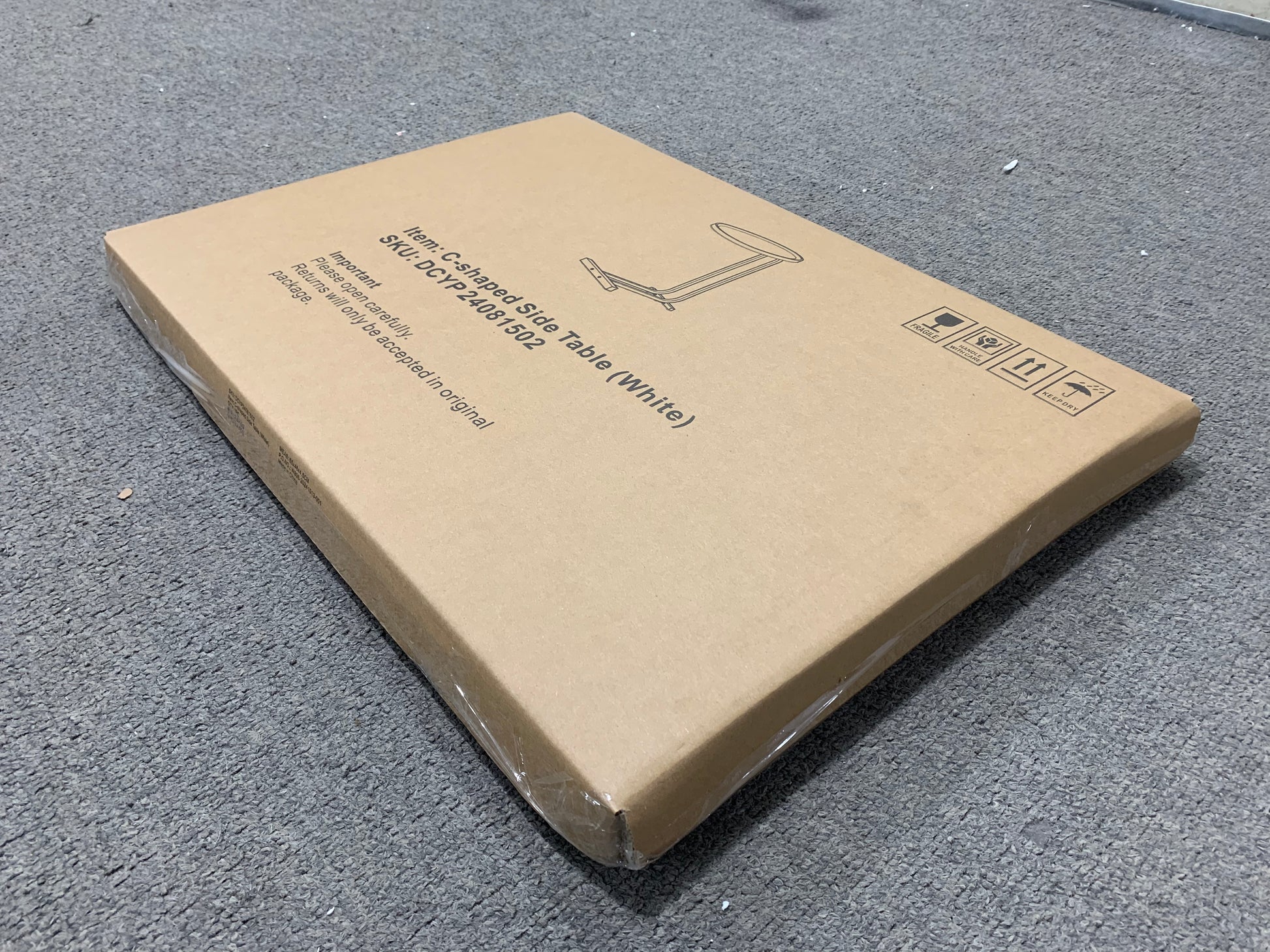Cardboard box packaging for a white Cshaped side table with assembly instructions printed on top