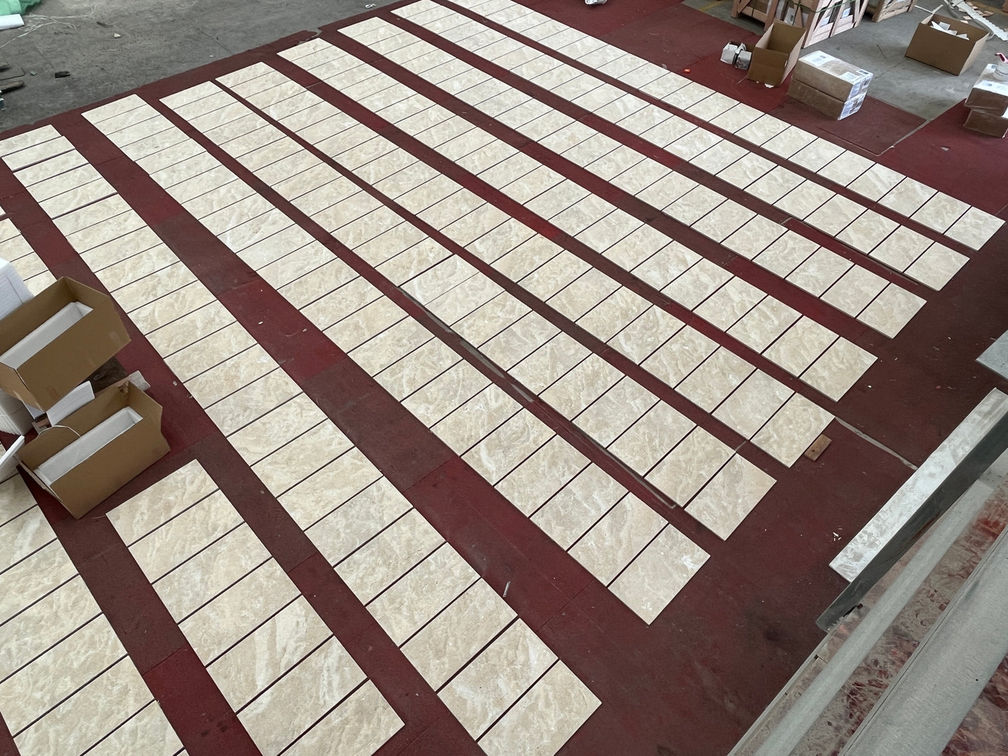 Beige marble floor tiles laid out in neat rows on a dark red floor