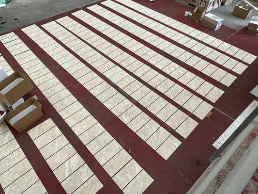 Beige marble floor tiles laid out in neat rows on a dark red floor