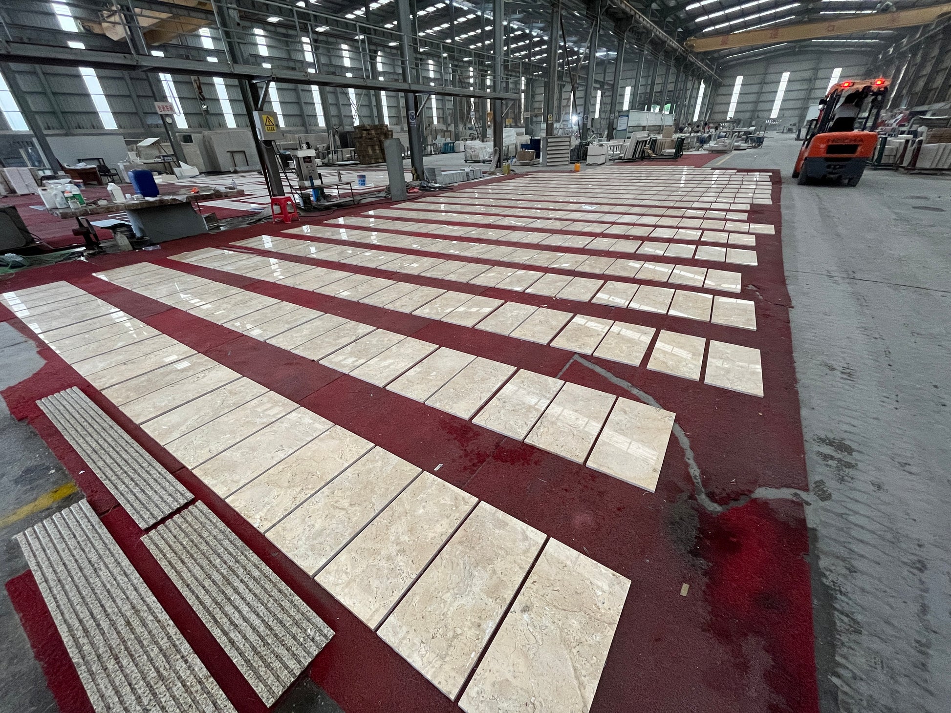 Beige marble tiles with subtle veining laid out in rows on a red carpet