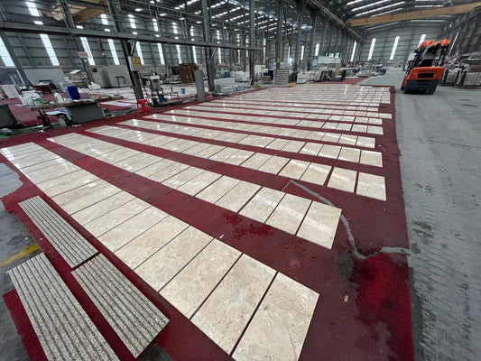 Beige marble tiles with subtle veining laid out in rows on a red carpet