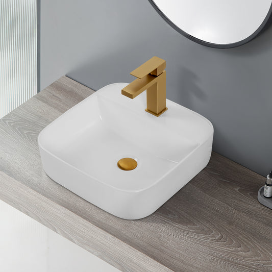 White ceramic vessel sink with brushed gold faucet and drain on a grey wood countertop