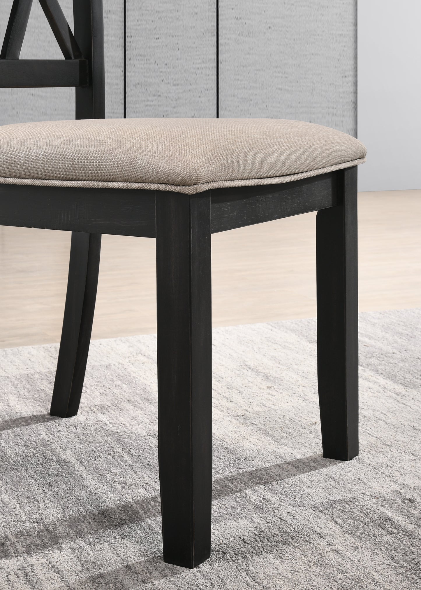 Closeup of dark wood dining chair leg with beige fabric seat