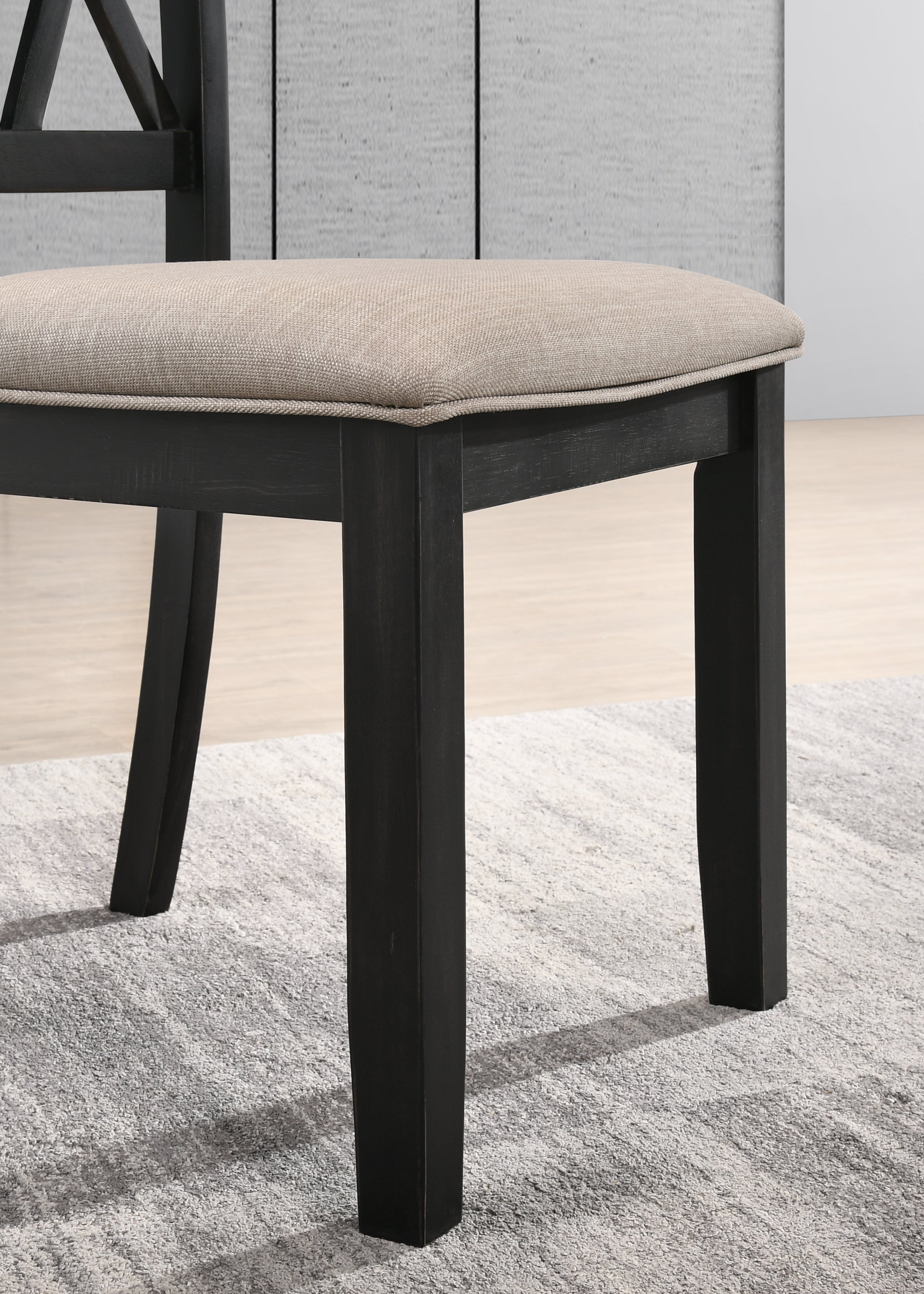 Closeup of dark wood dining chair leg with beige fabric seat