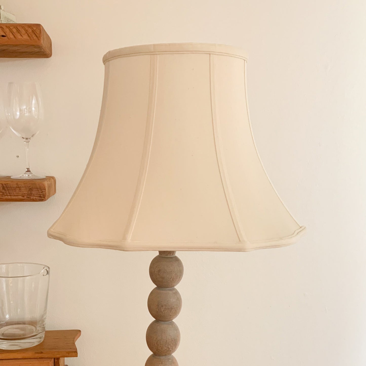 Cream fabric lampshade on a wooden ballstack base floor lamp