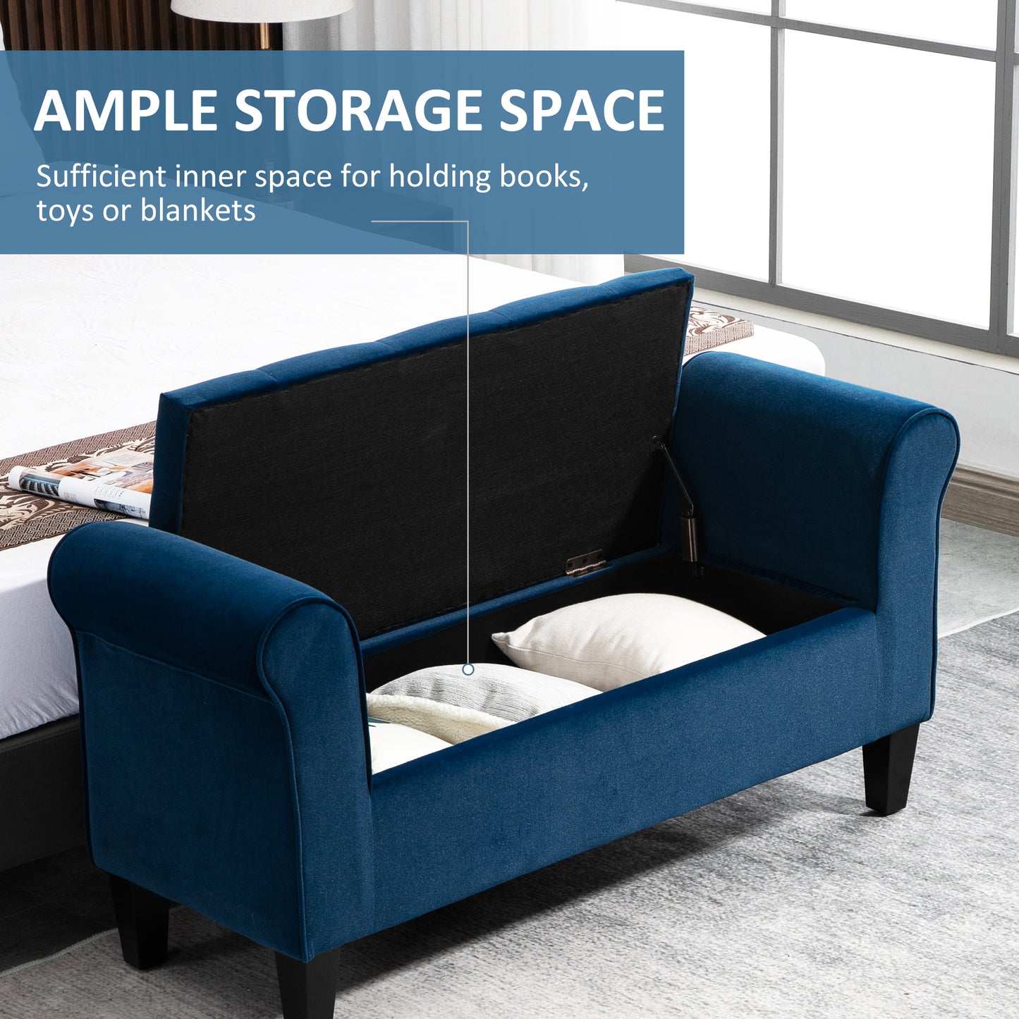 Open navy blue upholstered storage bench with rolled arms showing stored pillows and blankets